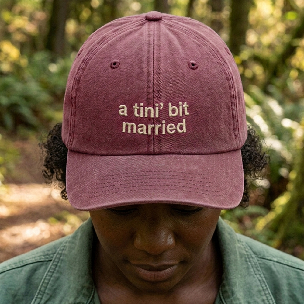 A female model wearing a premium hen do cap in red that has been embroidered with the phrase a tini bit married in a tusk font