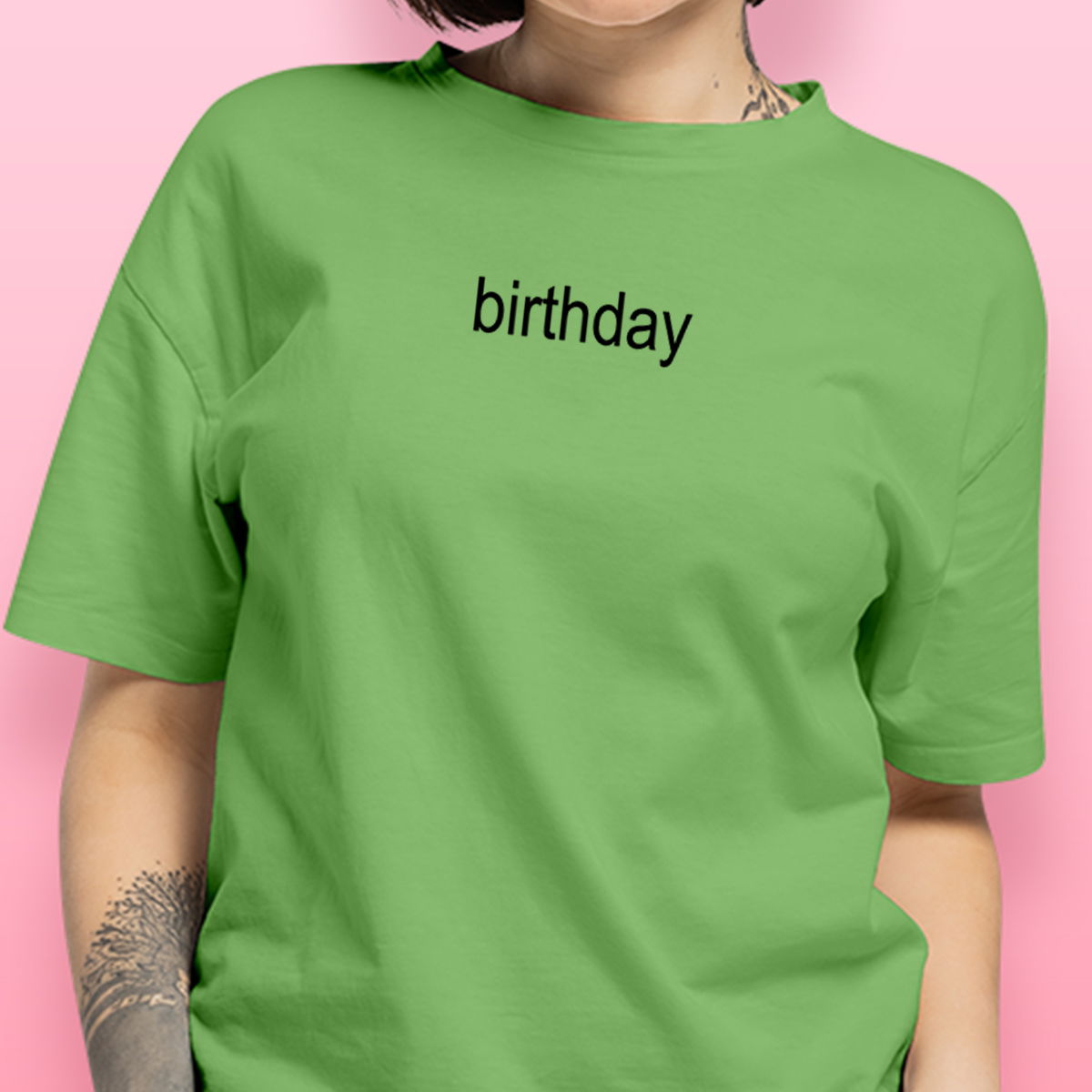 A model wearing a green shirt with the word 'birthday' on it in the iconic Brat font as inspired by Charli XCX. 