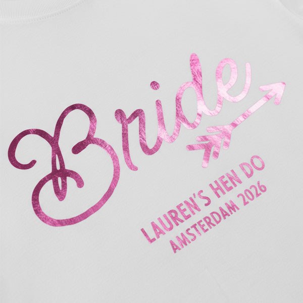 A white hen do shirt with custom shiny pink foil text that reads Bride, Lauren's Hen Do, Amsterdam 2026