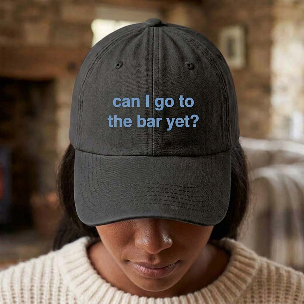 A female model wearing a premium hen do cap in grey that has been embroidered with the phrase can I go to the bar yet in a light blue font