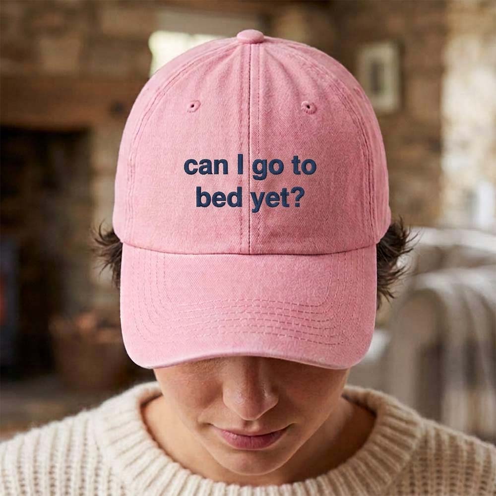 A female model wearing a premium hen do cap in pink that has been embroidered with the phrase can I go to bed yet in a navy font