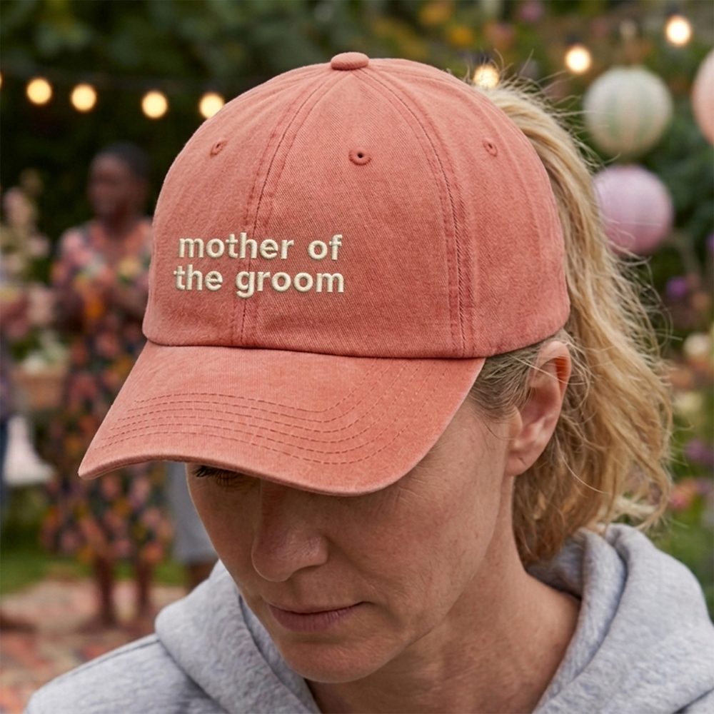 A female model wearing a premium custom hen do cap in orange that has been embroidered with mother of the groom in tusk text
