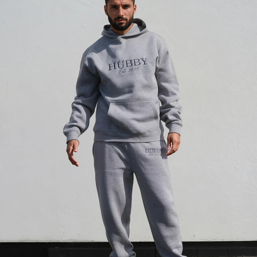 A male model wearing a luxe honeymoon hoodie that's embroidered with HUBBY 
