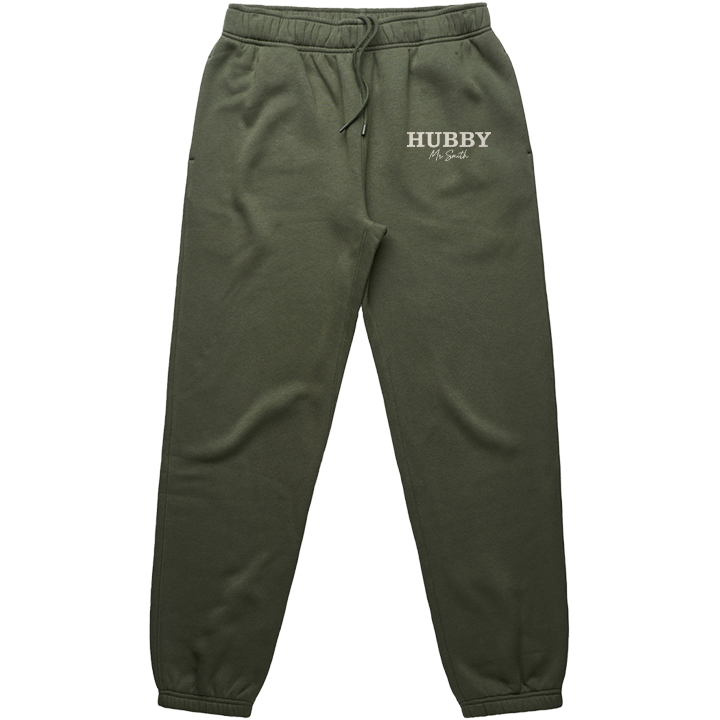 A pair of luxurious Cyprus green honeymoon joggers that have HUBBY embroidered on them in a statement capitalised font and underneath Mr Smith embroidered on it in a cursive font