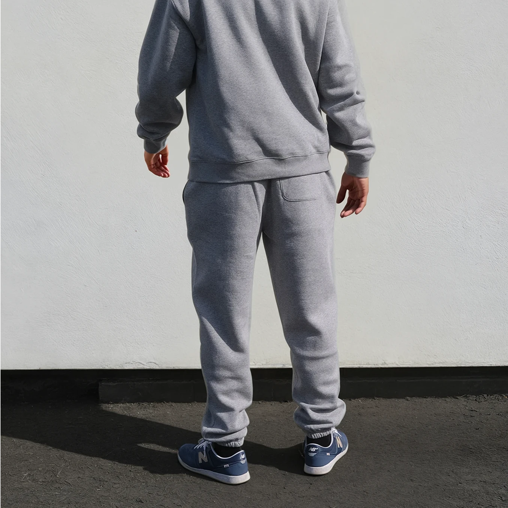 A back view of a male model wearing a athletic heather coloured luxurious looking hoodie and jogger combo