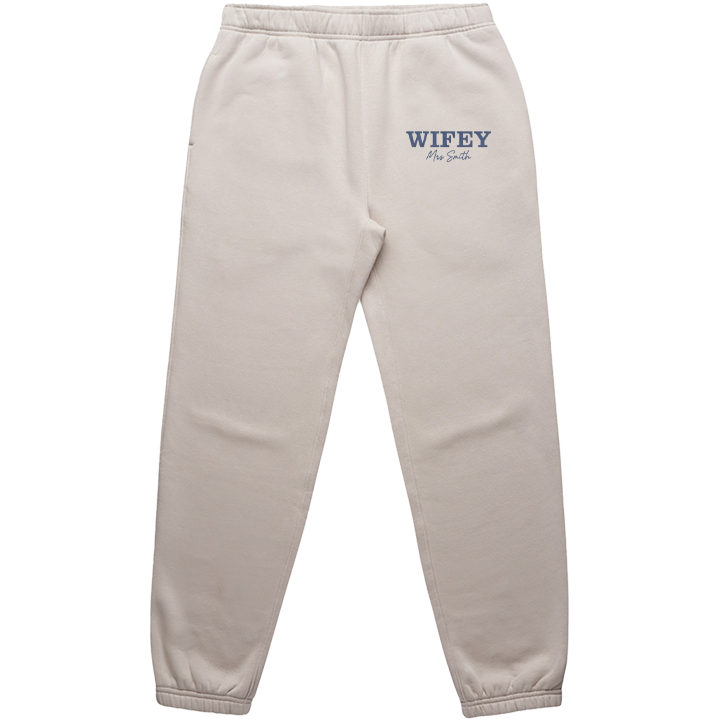 A luxurious pair of bone coloured honeymoon joggers that have WIFEY in statement text and Mrs Smith in cursive text embroidered on them 