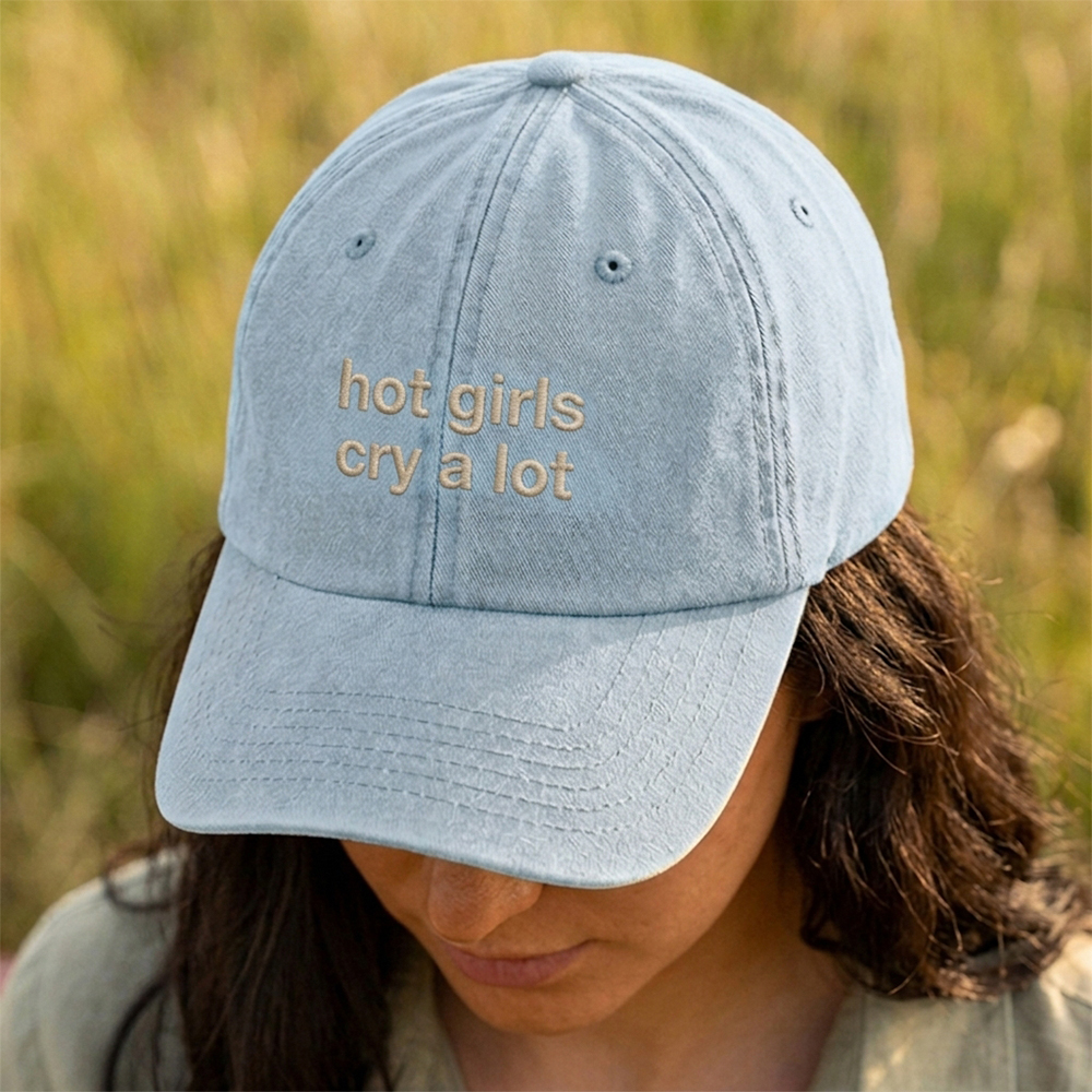 A female model stood in a field wearing a premium hen do cap in light blue with custom text hot girls drink cry a lot embroidered on it