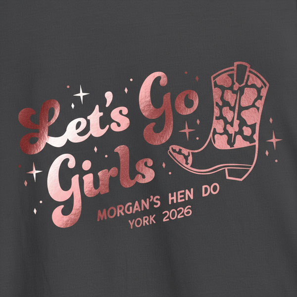 A black hen do shirt with custom shiny foil pink writing that has a cowboy boot on it and reads Let's Go Girls, Morgan's Hen Do, York 2026