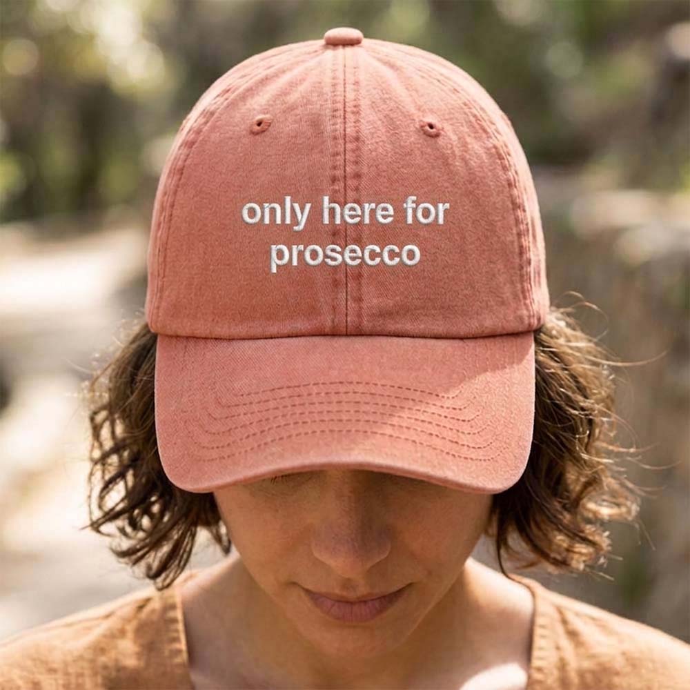 A female model wearing a premium hen do cap in red that has been embroidered with the phrase only here for prosecco in a super white font 