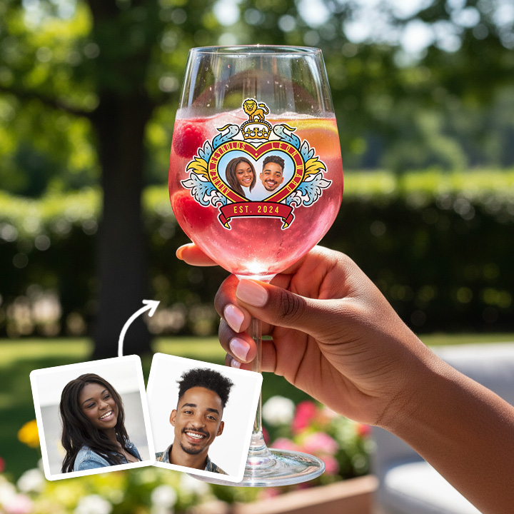 A custom glass with a pink liquid in it boasting a Royal Wedding style love heart design which has been personalised with a picture of a couple alongside their names and date they got married/together with a garden background