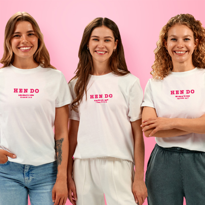 Three women all wearing custom hen do t shirts that read Hen Do, Helena's Hen, Tenerife 2026 in a subtle pink font
