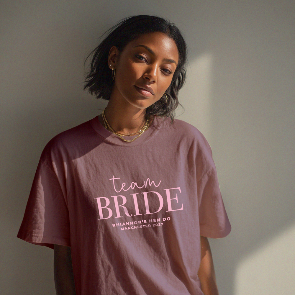 A female model wearing a red custom hen do t shirt with editable text that reads Team Bride, Joanna's Hen Do, Newcastle 2026