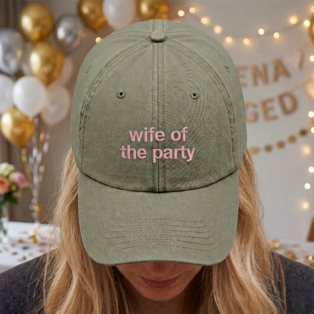 A female model with a hen do party blurred background wearing a premium hen do cap in green with the text wife of the party embroidered on it