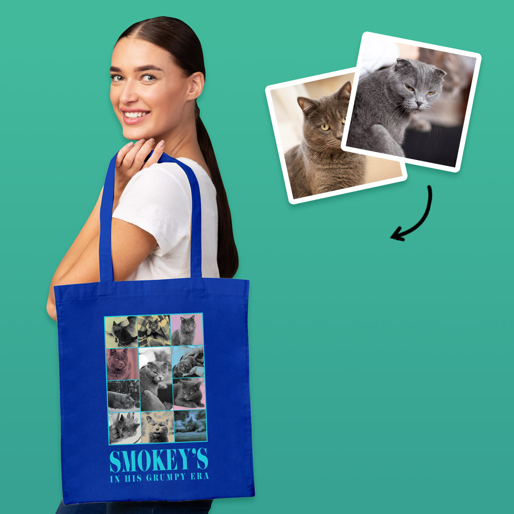 A female model wearing a blue Eras themed tote bag that has been personalised with loads of pictures of a grey cat and the custom text Smokey's In His Grumpy Era
