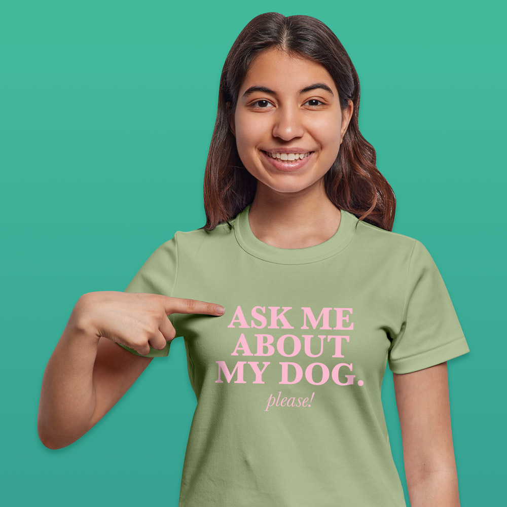 A female model wearing a light green pet t shirt with pink writing that reads 