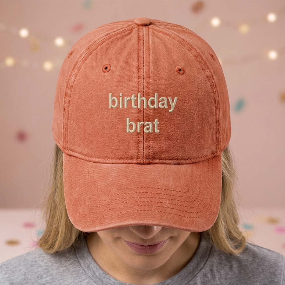 A female model wearing a premium hen do cap in brown that has been embroidered with the phrase bikinis and martinis in a blue font
