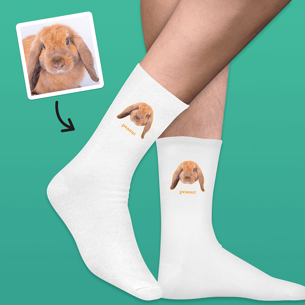 A pair of white socks that can be customised with the face of a pet and up to two lines of custom text that have a picture of a rabbit on each sock with the word peanut underneath it