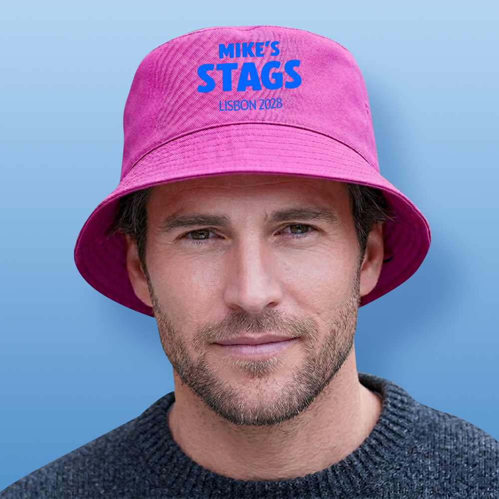 A male model wearing a pink custom stag do bucket hat with the custom text Mike's Stags Lisbon 2028 in a blue bold font