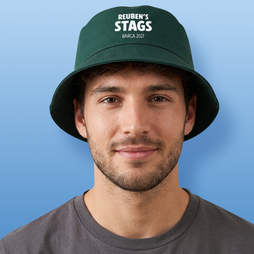 A male model wearing a green custom stag do bucket hat with the custom text Reuben's Stags Barca 2027 in a white bold font