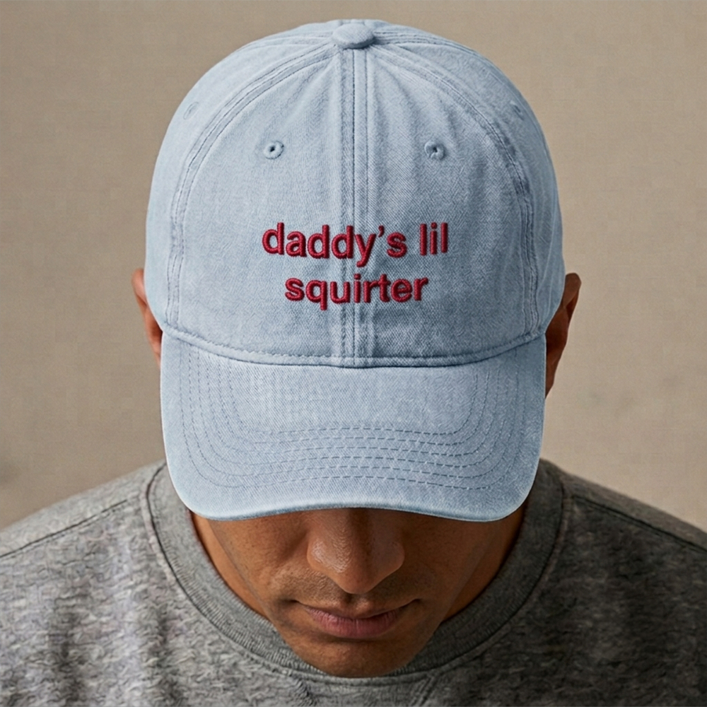 A male model wearing a rude premium vintage cap in blue that has been embroidered with daddy's lil squirter in red coloured thread