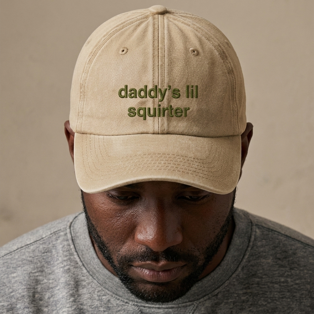 A male model wearing a rude premium vintage cap in sand that has been embroidered with daddy's lil squirter in green coloured thread