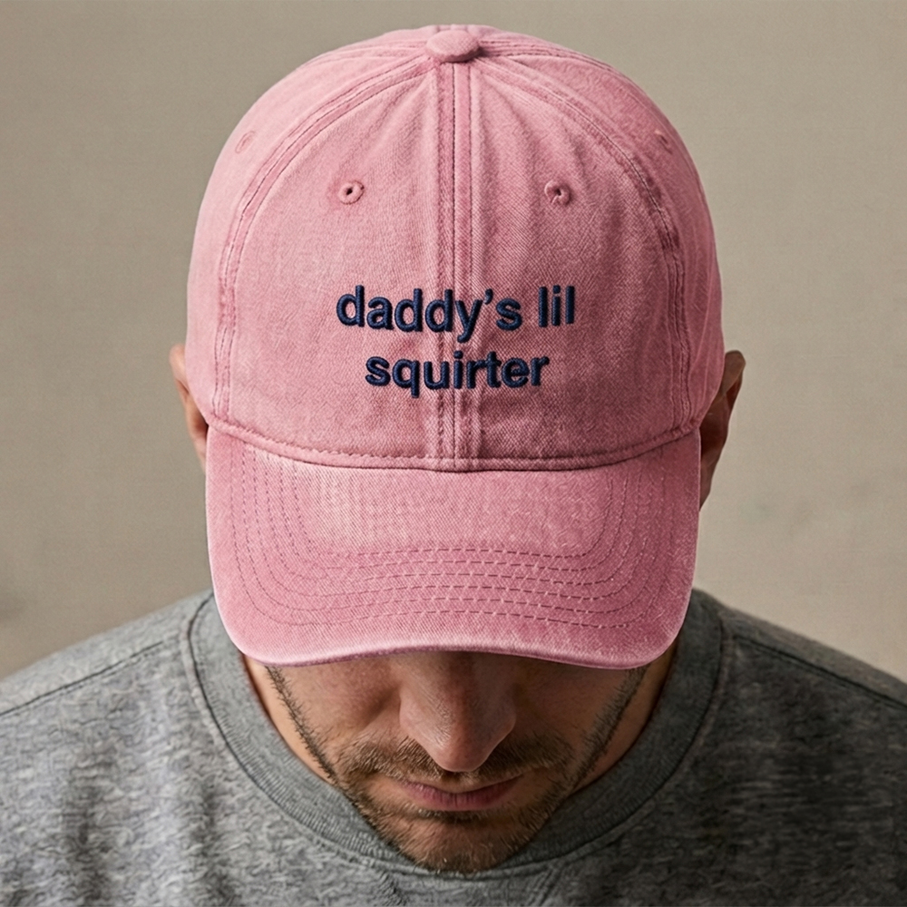 A male model wearing a rude premium vintage cap in pink that has been embroidered with daddy's lil squirter in blue coloured thread