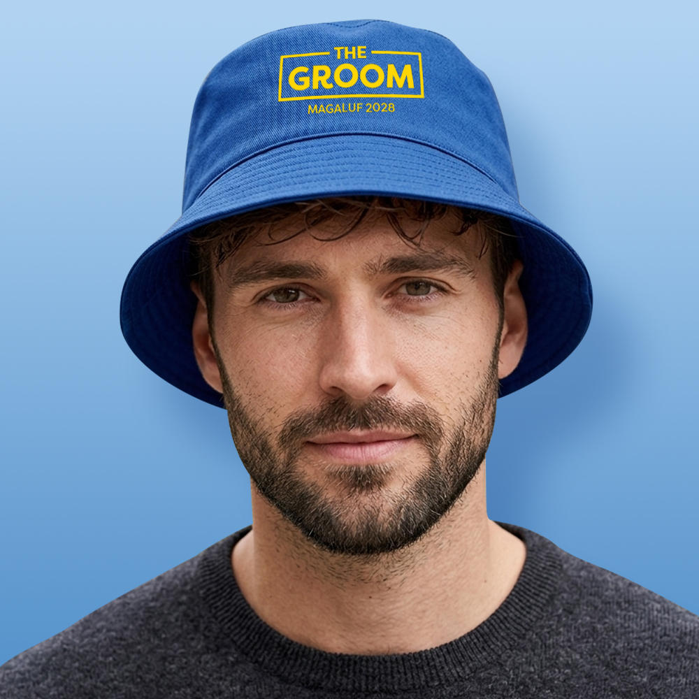 A male model wearing a blue custom stag do bucket hat that reads The Groom which is in the middle of a rectangular box with Magaluf 2028 below it
