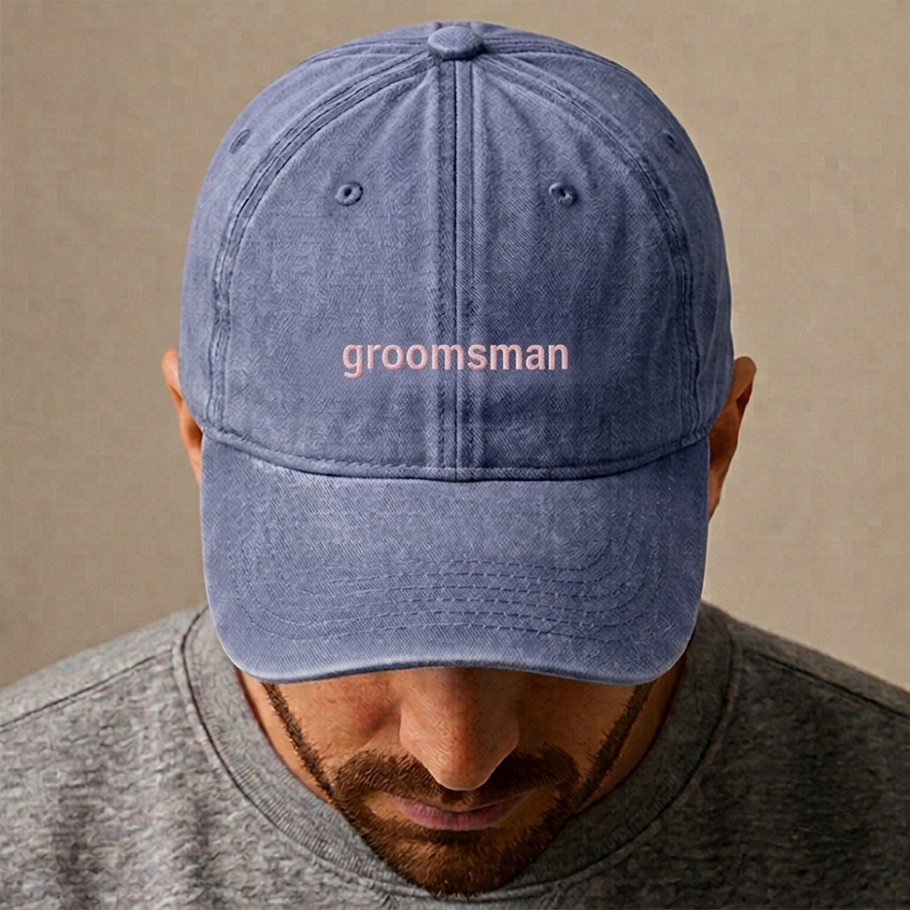 A male model wearing a premium custom stag do cap in blue that has been embroidered with groomsman in pink text