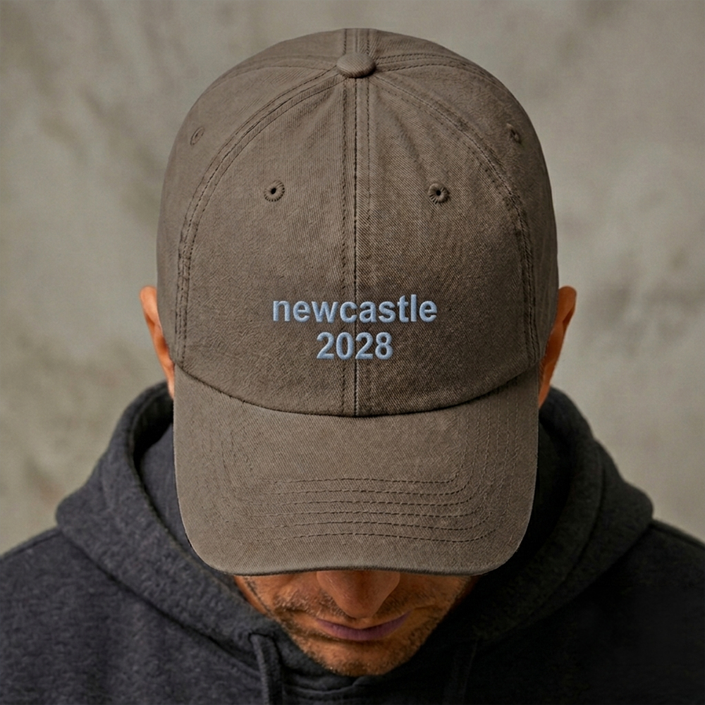 A male model wearing a custom text premium vintage cap in brown that has been embroidered with newcastle 2028