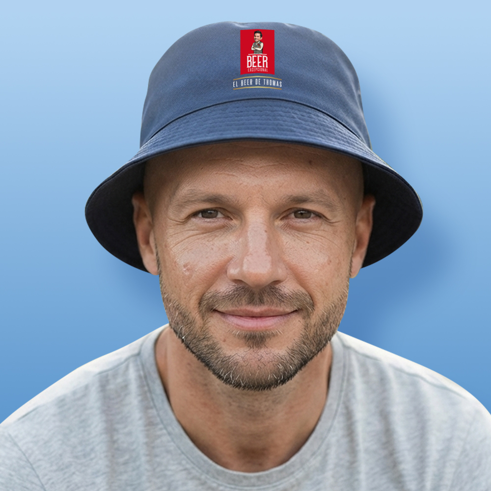 A male model wearing a blue custom Madri-themed bucket hat which has been personalised with a photo of a man's face integrated into the Madri man logo with custom text reading El Beer De Thomas