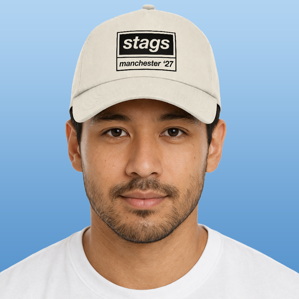 A male model wearing a natural coloured Oasis style custom cap that reads stags manchester '27 in the style of the Oasis logo