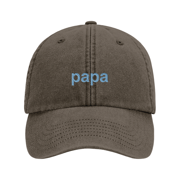 A premium vintage cap Father's Day cap in vintage brown that has been embroidered with the word papa in blue font 