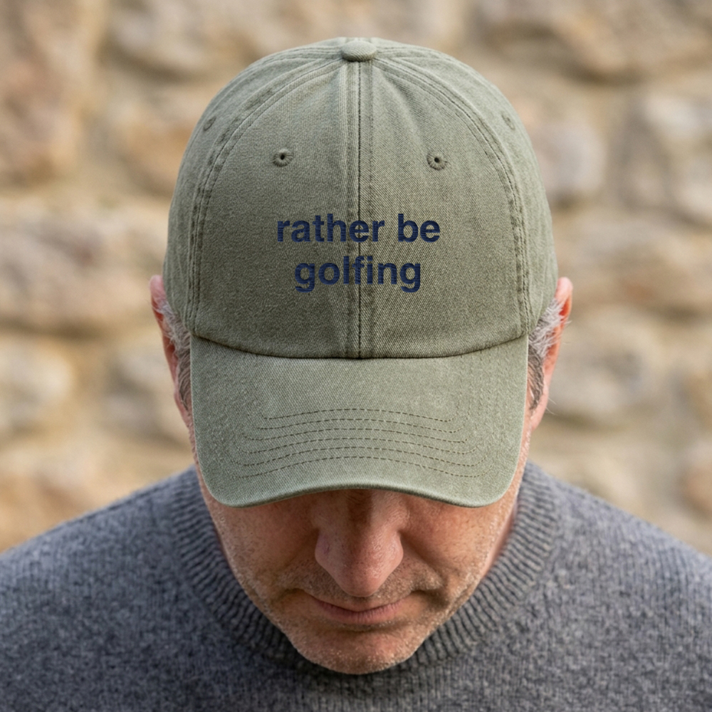 A male model stood in front of a blurred background wearing a premium vintage embroidered Father's day cap in green with custom text reading rather be golfing in blue font