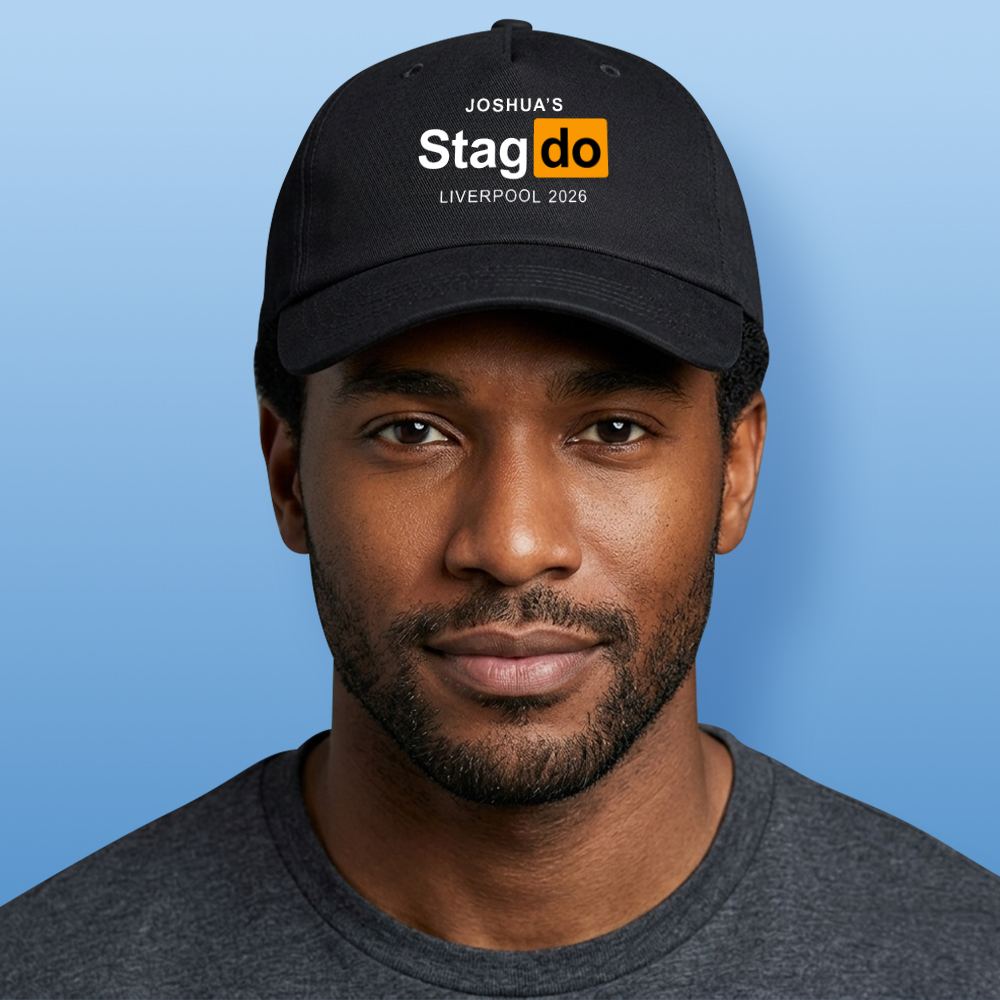 A male model wearing a natural coloured Oasis style custom cap that reads stags manchester '27 in the style of the Oasis logo