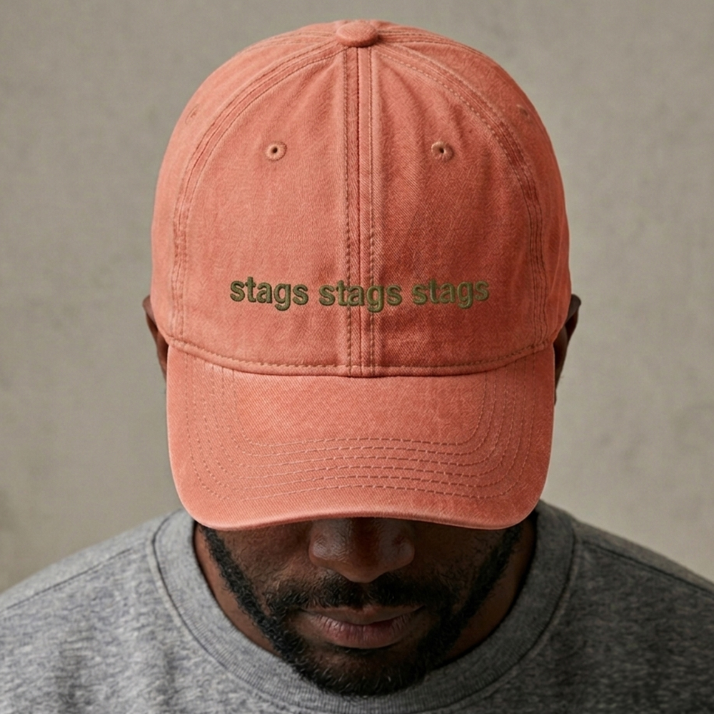 A male model wearing a premium custom stag do cap in orange that has been embroidered with stags stags stags in green text