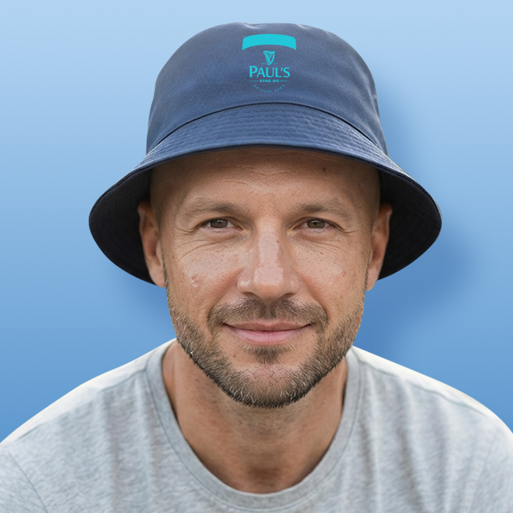 A male model wearing a blue custom stag do bucket hat with the Guinness logo reading Paul's Stag Do Belfast 2027