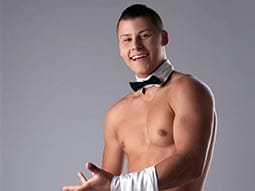 Close up of a man wearing a dickie bow tie and nothing else with a white tea towel over his arm