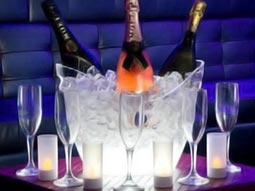 Various bottles of alcohol inside an ice bucket, with glasses surrounding it