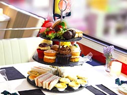 A serving tray with three tiers of cakes and sandwiches