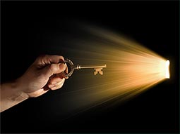 A close up of a hand, holding a key up to a light