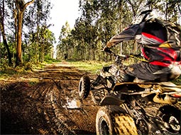 Someone on a quad bike riding through muddy terrain