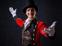 A man in a red jacket and white gloves, with his arms in the air