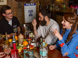 A group of people sitting at a table with a variety of gins and fruit on it at Brewhouse & Kitchen