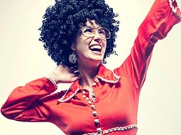 A woman in red flared bodysuit, black afro and sunglasses