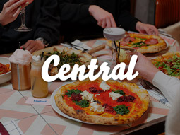 Two cocktails on a table surrounded by plates of pizza