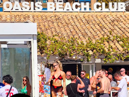 People sat having drinks with the Oasis Beach Club logo overlayed