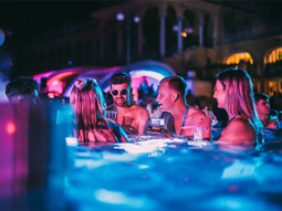 A group of people in a pool lit with pink lights at Sparty in Budapest