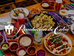 Tapas and cocktails on a table with the Revolución de Cuba logo overlayed
