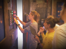 A woman trying to solve a key code on a door whilst her friends watch on 