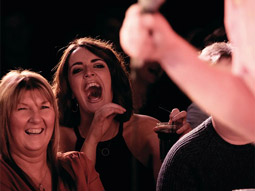 People in the crowd laughing at a comedian on stage at Glee Comedy Club